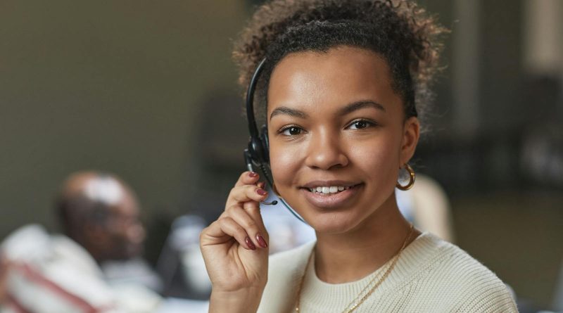 Femme sympathique dans un centre d'appel, portant un casque et souriante.