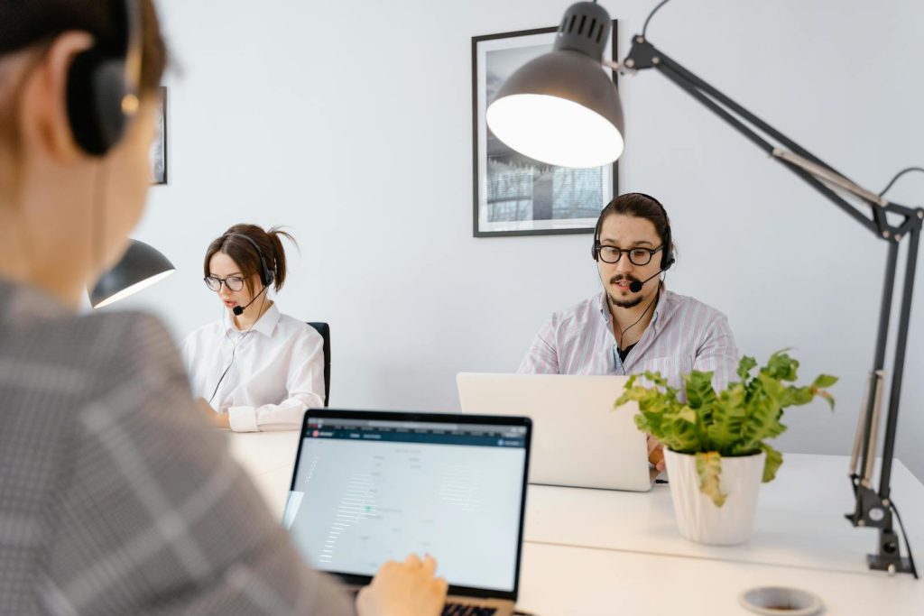 Agents professionnels d'un centre d'appel travaillant sur des ordinateurs portables dans un bureau moderne et lumineux.